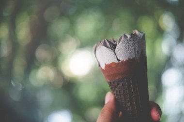 Dondurmalı çikolatalı gofret külahını bulanık bir arka planda tutan bir adam. Tatlı menü konsepti.