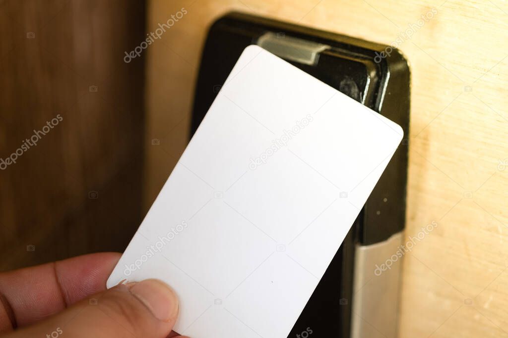 Hand using electronic smart key card for unlock door in hotel or house.