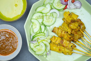 Fıstık sosu ve sebze turşusuyla servis edilen yeşil tepside domuz eti..