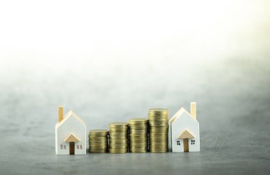 Altın sikkeleri olan küçük bir ev modeli. Emlak yatırımı veya ev kredisi