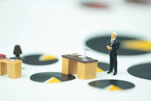 Miniature people businessman standing with table work desk on chart black and yellow circle for analysis business