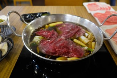 Japon lokantasında sukiyaki ya da shabu yapmak için et ve sebze pişirmek.