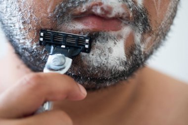 Usturayla tıraş olan bir adama yakın çekim.