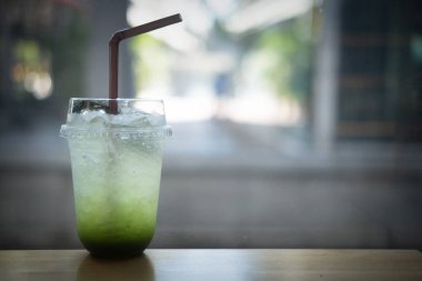 Elmalı gazoz, masanın üzerinde plastik camla buz.