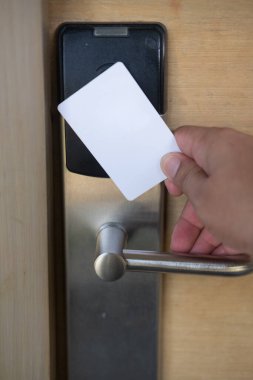 Adam otel odasının kapısını açmak için anahtar kartını kullanıyor. Kapı erişimi için mıknatıs kartı tutuluyor kapıyı kilitleyip açmak için anahtar kartı taranıyor