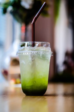 Elmalı gazoz, masanın üzerinde plastik camla buz.