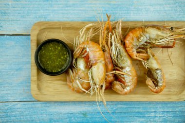 Izgara karides ve ahşap tepside baharatlı Tayland deniz ürünleri sosu.