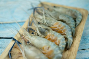 Bol yumurtalı taze çiğ karides, ahşap tepside pişirmeye hazır.