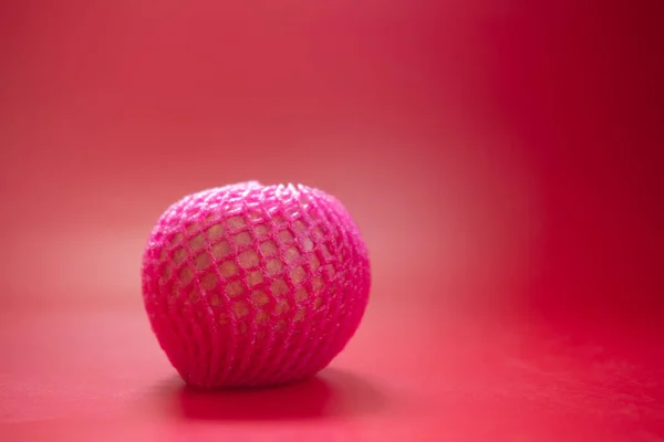 红苹果 用粉色泡沫网包裹 红色背景 — 图库照片