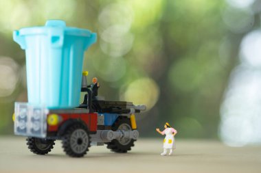 Minyatür işadamı çöp arabasında oturuyor. Atık ayıklama ve işleme işi.