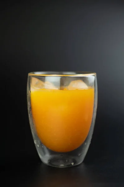黒の背景にアイスキューブと新鮮な絞りオレンジジュース — ストック写真