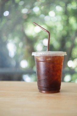 Bir bardak ferahlatıcı soda, buz küpleri ve ahşap masada saman.