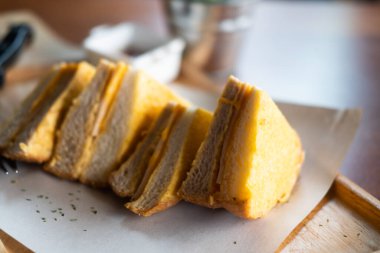 Ahşap tepside kızarmış jambonlu ve peynirli sandviç.