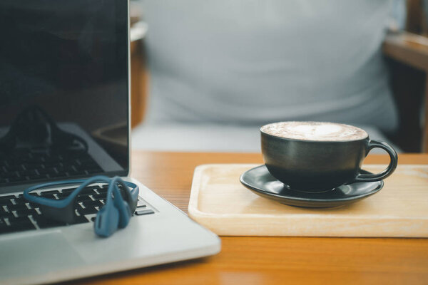 A cup of hot dark chocolate on wooden table with  laptop. Drink for hot drink break after working or weekend meeting. Office desk table