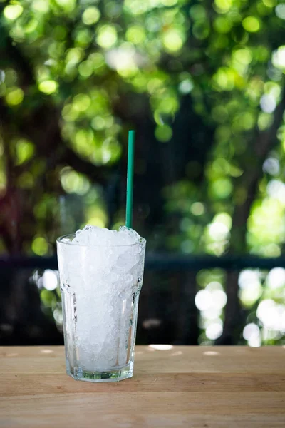 Glass of crushed ice with tube green standing on the empty bar