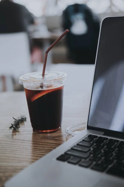 Black iced coffee with a notebook on wood table. Coffee break beverage cafe drinking enjoyment concept