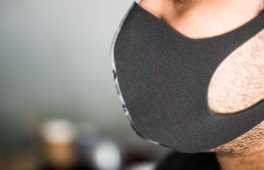 Siyah maskeli bir adam yan duruyor. Enfeksiyonlardan korunmak için maske takma ihtiyacı..