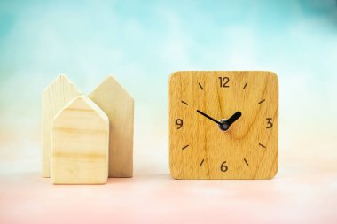 Tahta oyuncak ev ve pastel arka planda ahşap saat