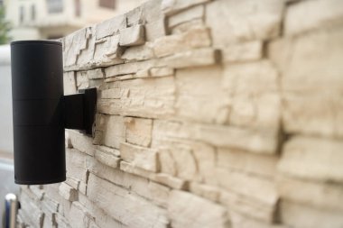 Bahçedeki tuğla duvar süslemesindeki siyah LED aşağı ışık dekorasyonunu kapat. Sığ görüş derinliği