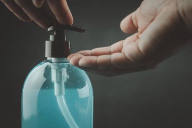 Adam Coronavirus 'tan el dezenfektanı jeli temizleme jeli kullanıyor. Siyah arka planda COVID 19.