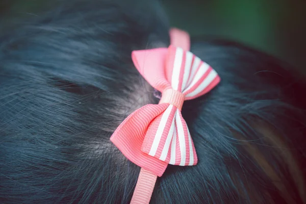 可爱女孩头上有条纹图案的漂亮粉色蝴蝶结 — 图库照片