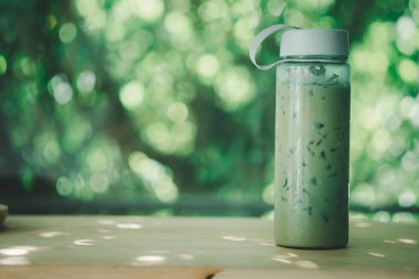 Plastik şişede buzlu kahve, ahşap masada yeşil kapaklı. Sıfır atık kampanyası kavramı