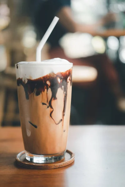 Iced mocha coffee with chocolate cream poured into glass it showing the texture and refreshing look of the drink. Coffee shop menu. Vertical photo.
