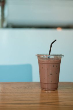 Ahşap masanın üzerinde plastik camlı buzlu kakao.