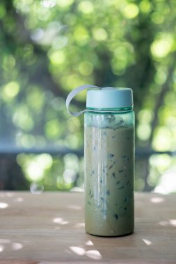 Plastik şişede buzlu kahve, ahşap masada yeşil kapaklı. Sıfır atık kampanyası kavramı
