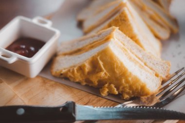 Ahşap tepside kızarmış jambonlu ve peynirli sandviç.