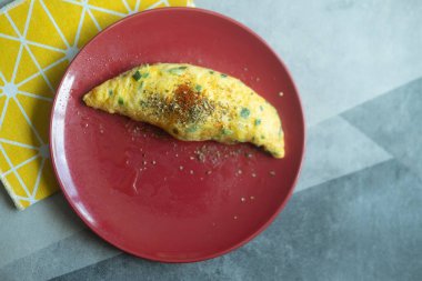 Kırmızı tabakta taze soğanlı omlet rulosu.