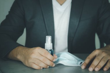 Alkol dezenfektanı ve sağlık maskesi olan bir iş adamı. 2020 Corona virüs krizinde insanları yüz maskesi kullanarak virüs enfeksiyonundan koruyorlar.