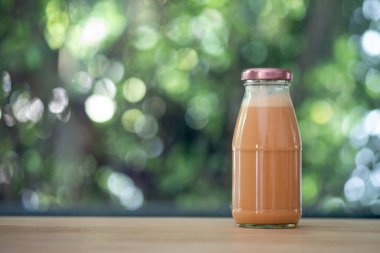 Soğuk Thai sütlü çay, cam bir şişede, ahşap masaya konur.