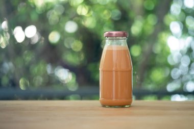 Soğuk Thai sütlü çay, cam bir şişede, ahşap masaya konur.