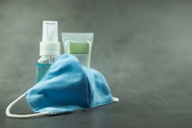 Mavi kumaş maskeyi el jeli ve alkol spreyiyle kapat. Bakteri yoluyla koronavirüsü önleme.