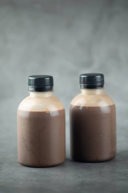 Siyah arka planda iki plastik kakao sütü şişesi.