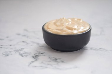 Sezar salatası kreması mermer masada siyah bir fincanda.