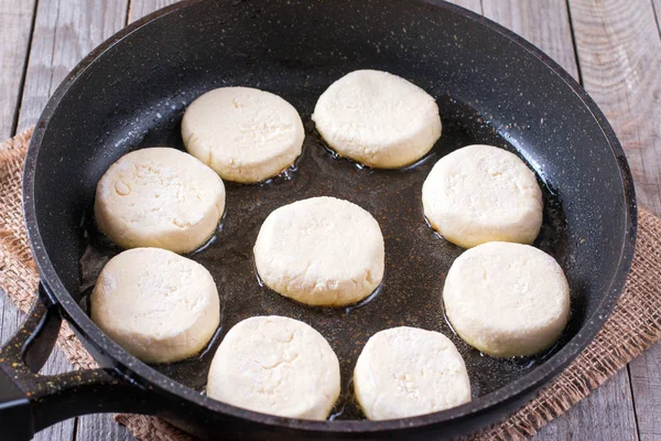 Сырые сироники (блинчики с сыром) на сковородке — стоковое фото