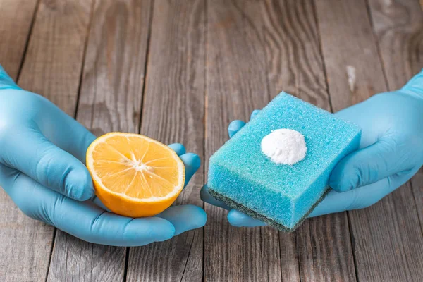 cleaning tools and sodium bicarbonate in hand on wooden table