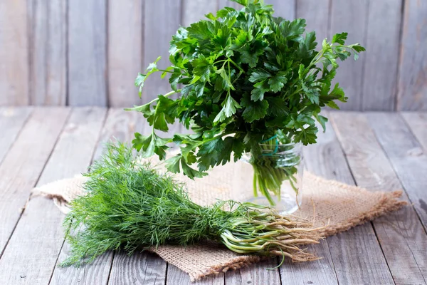 Fresh garden dill and parsley herbs on wooden table