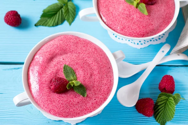 Raspberry mousse in a white bowl on blue wooden table — Stock Photo, Image