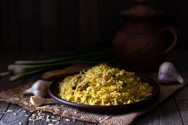 Delicioso pilaf em uma placa marrom em um fundo de madeira — Fotografia de Stock