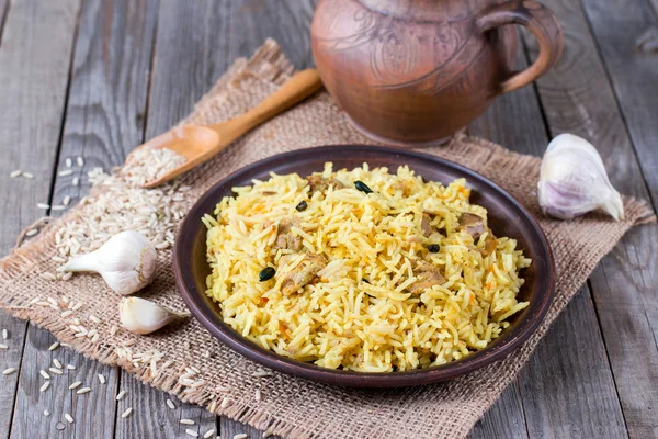 Pilaf sobre un plato marrón sobre un fondo de madera —  Fotos de Stock