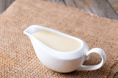 Ahşap bir masa bir sos teknede Beşamel sos