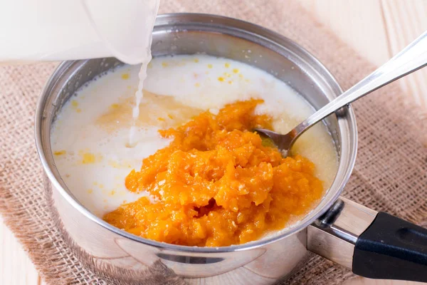 Cooking pumpkin porridge with milk in a saucepan — Stock Photo, Image