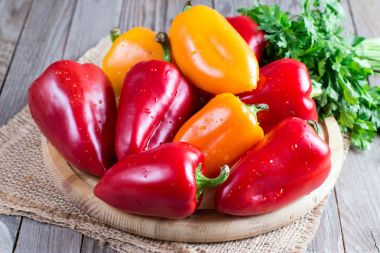 Bir kesme tahtası ahşap arka plan üzerinde kırmızı ve sarı biber