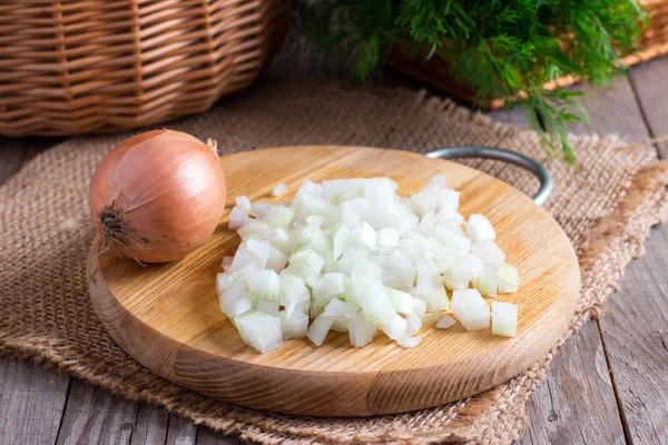 Cebola crua, cubos muito pequenos picados em uma tábua de madeira — Fotografia de Stock