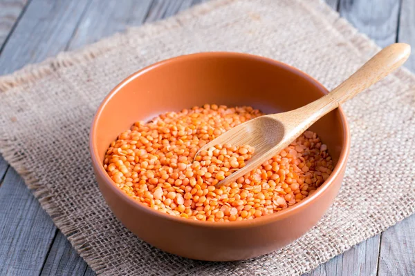 Red lentils in a ceramic bowl on a wooden background — Stock Photo, Image