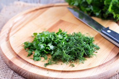 Yeşil otlar kesme tahtası üzerinde kıyılmış.