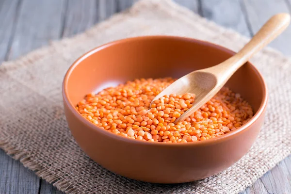 Red lentils in ceramic bowl on wooden table — Stock Photo, Image